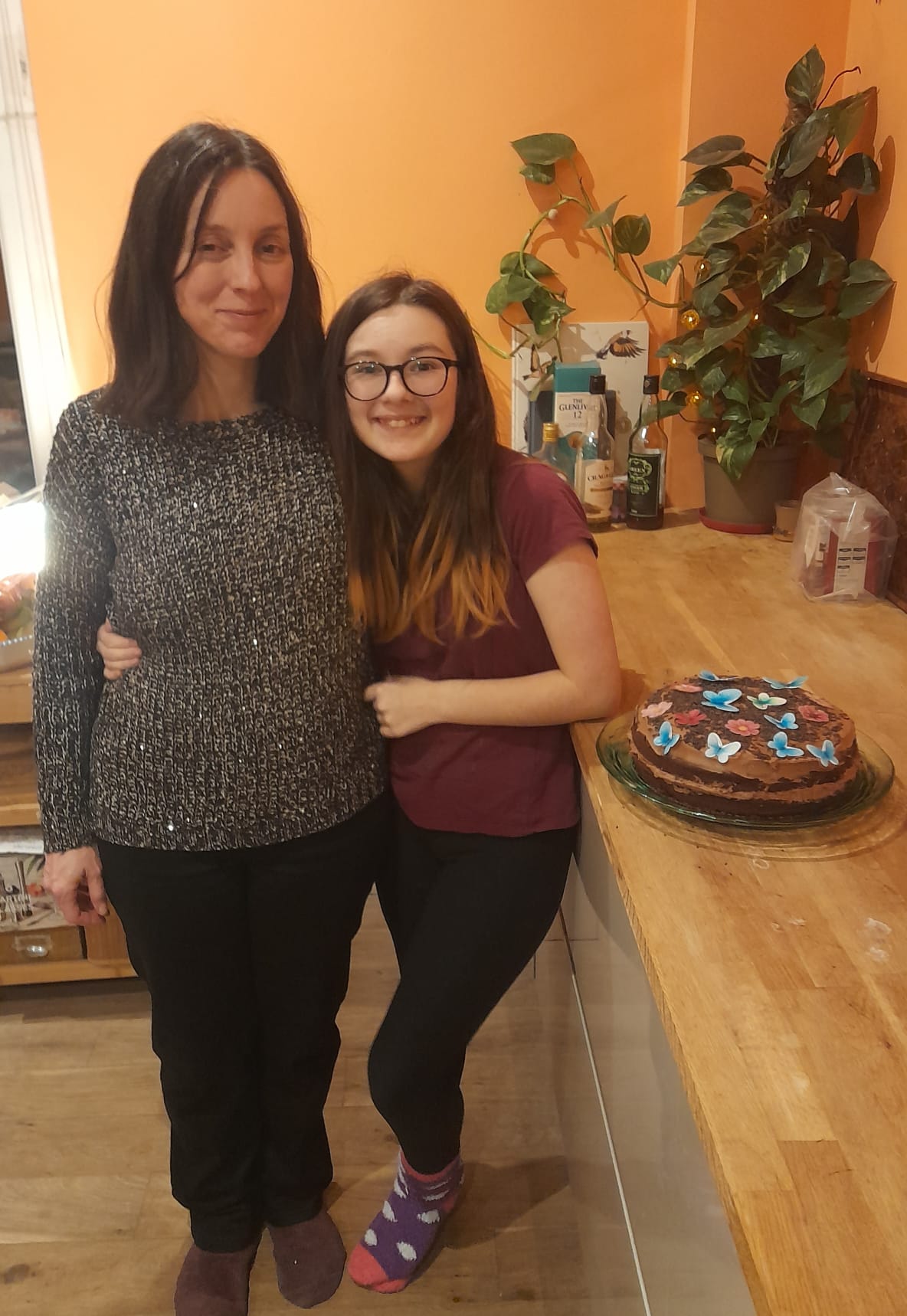 Woman_with_brown_hair_cuddling_her_brown_haired_daughter_who_wears_glasses