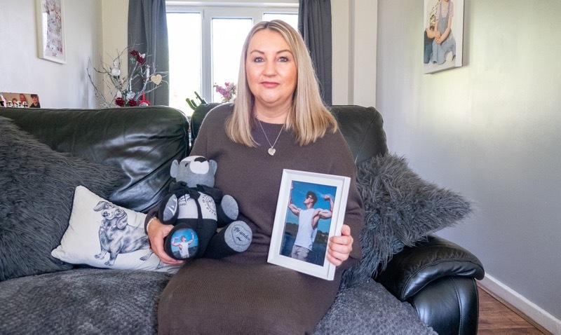 woman_with_blond_hair_sitting_on_a_sofa_holding_a_teddy_bear_and_a_photograph