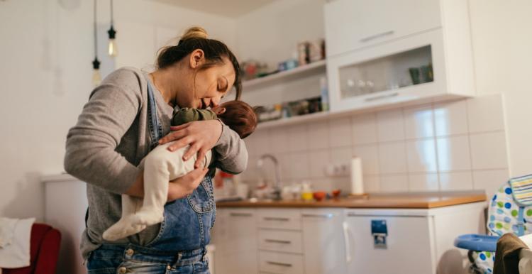 Woman_holding_new_baby_in_her_kitchen