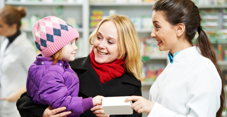 Woman_holding_a_child_wearing_a_hat_visting_a_pharmacist_all_are_smiling