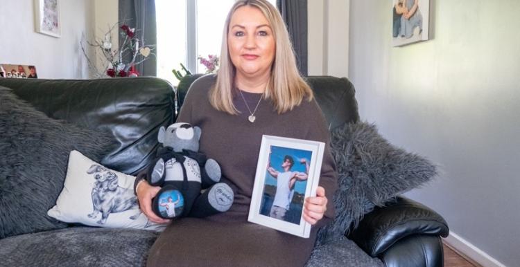 woman_with_blond_hair_sitting_on_a_sofa_holding_a_teddy_bear_and_a_photograph