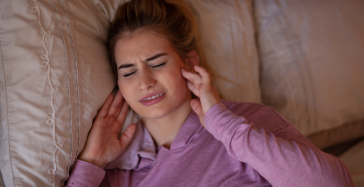 woman_holding_her_jaw_in_pain_and_lying_on_a_bed