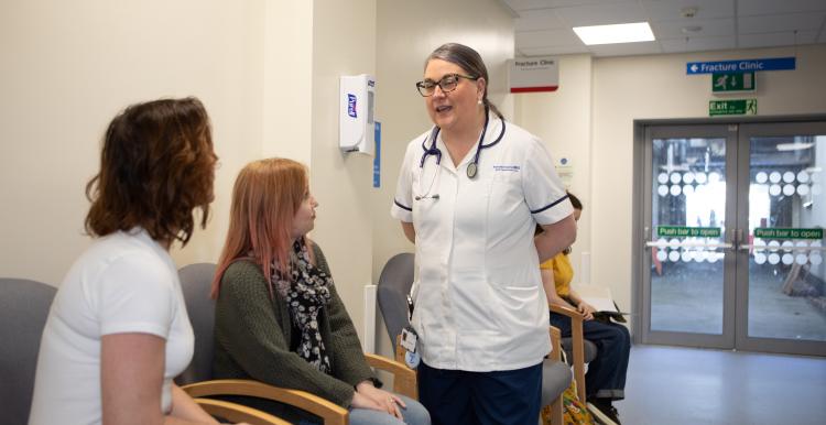 women_sitting_in_a_waiting_room_with_a_nurse_talking_to_them