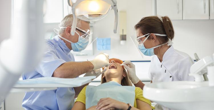 Male_dentist_and_female_dental_assistant_doing_a_dental_check_on_a_young_woman
