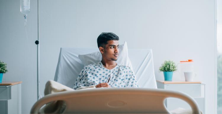 Young man laid in a hospital bed, staring out of the window