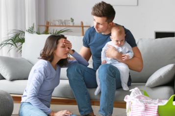 woman_upset_whilst_man_holding_baby_sits_and_listens