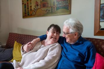 grey_haired_man_cuddling_brown_haired_woman_on_the_sofa