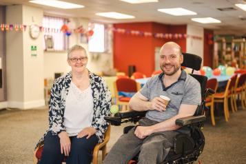 Older_lady_caring_for_a_disabled_man_in_a_wheelchair