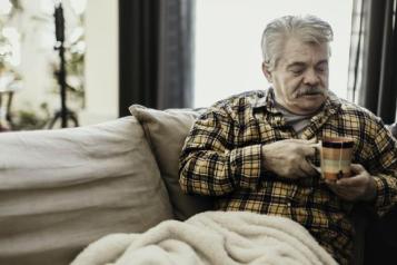 Old_man_cold_sitting_at_home_with_a_blanket_and_a_warm_drink