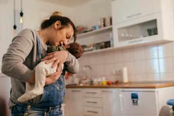 Woman_holding_new_baby_in_her_kitchen