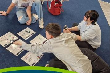 young woman sat on the floor talking to 2 young people