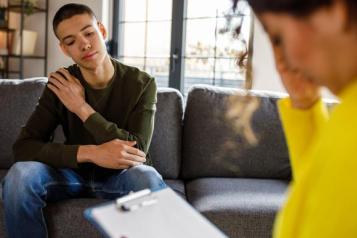 young_man_sitting_on_a_sofa_listening_to_a_woman_therapist