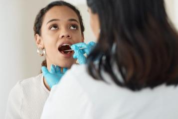 Young_woman_with_her_mouth_open_being_examined_by_a_dentist