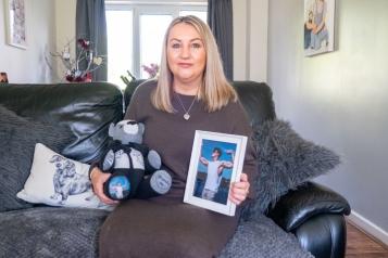 woman_with_blond_hair_sitting_on_a_sofa_holding_a_teddy_bear_and_a_photograph