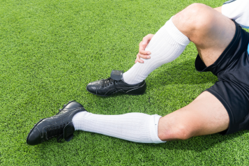 A_young_person_wearing_football_boots_holiding_their_shin