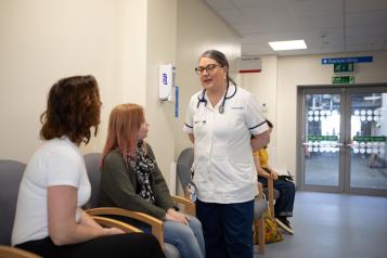 women_sitting_in_a_waiting_room_with_a_nurse_talking_to_them