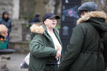 middle_aged_woman_wearing_a_green_parker_coat_and_a_baseball_hat_talking_to_a_man_also_wearing_a_green_parker_coat