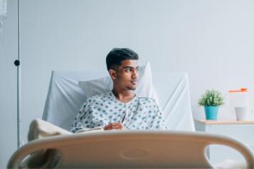 Young man laid in a hospital bed, staring out of the window