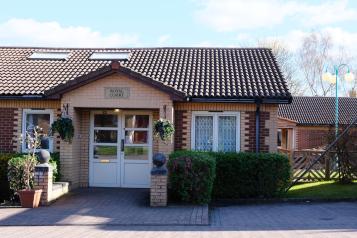 Photograph of the enterance to a building showing white double doors and a overhead canopy