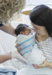 white-midwife-looking-after-an-asian-mother-and-child