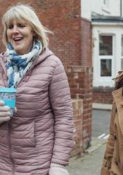women_walking_down_the_street_talking_and_drinking_coffee