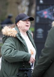 middle_aged_woman_wearing_a_green_parker_coat_and_a_baseball_hat_talking_to_a_man_also_wearing_a_green_parker_coat