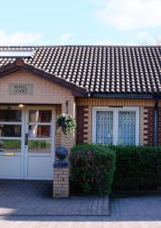 Photograph of the enterance to a building showing white double doors and a overhead canopy